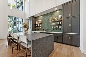 A modern kitchen with a large island, dark cabinets, and a green backsplash. - Landing Apartments near Lakes of Forest Hill (Cordova)