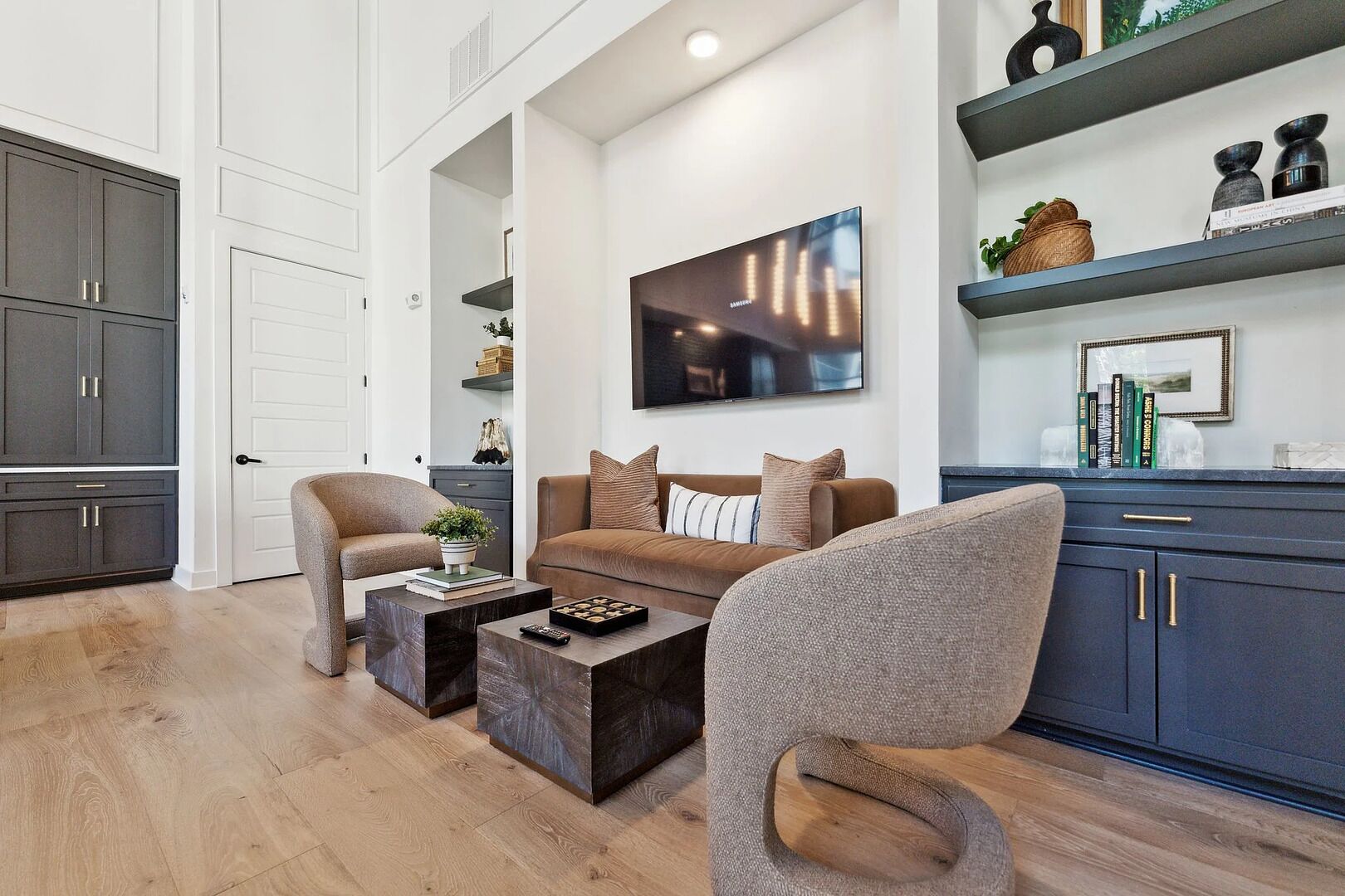 A modern living room with a sofa, two armchairs, a coffee table, and a flat-screen TV.