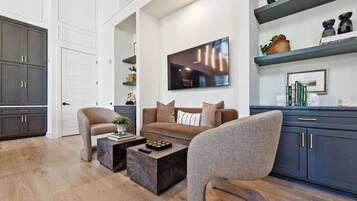 A modern living room with a sofa, two armchairs, a coffee table, and a flat-screen TV.