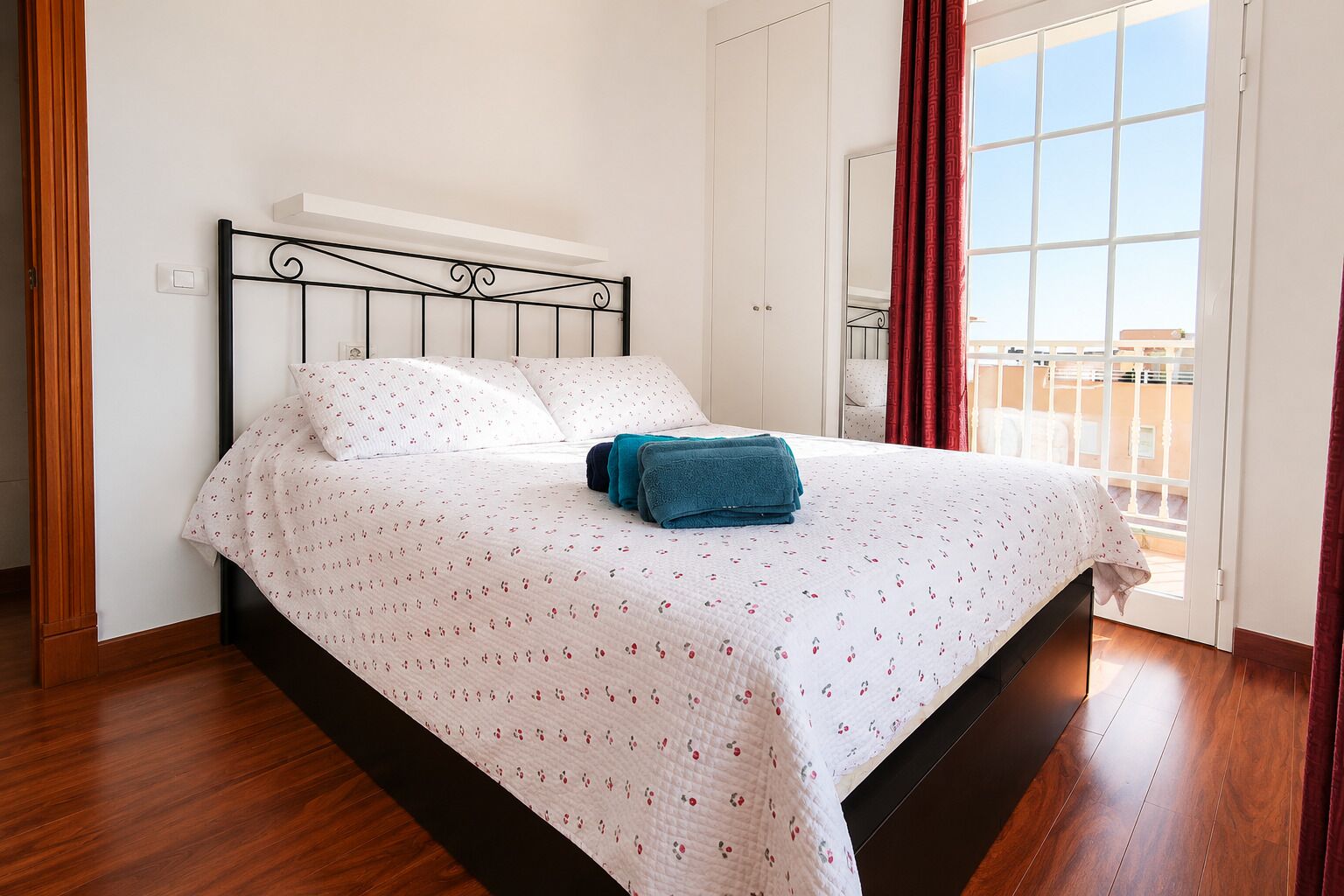 Un dormitorio con cama, ventana con cortinas y vistas a edificios.