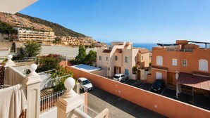 Un barrio residencial con vista al mar, con casas escalonadas y un cielo despejado.