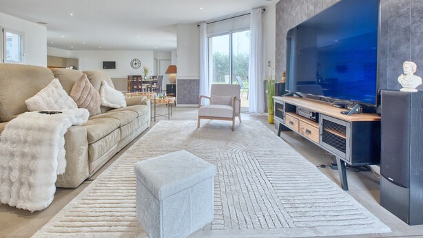 A modern living room with a large flat-screen TV, a sofa, a coffee table, and a minimalist design. - Spacious House with Garden & Terrace – Perfect for Families & Friends (Champcevinel)