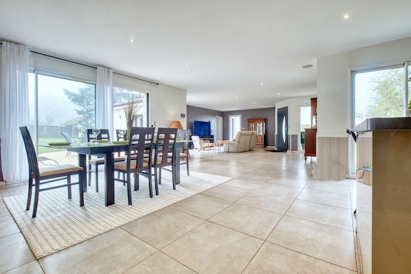 Un vaste espace de vie comprenant une table à manger, des chaises et une grande fenêtre.
