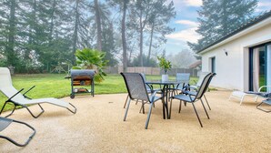 A patio with a table and chairs, a grill, and a view of trees and a building. - Spacious House with Garden & Terrace – Perfect for Families & Friends (Champcevinel)