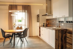 A modern kitchen with white cabinets, a wooden countertop, and a built-in sink. - Apartment-Fürstenau (Fürstenau)