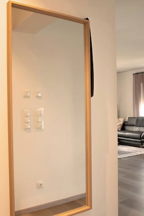 A room with a large mirror, a sofa, and a light-colored carpet. - Apartment-Fürstenau (Fürstenau)