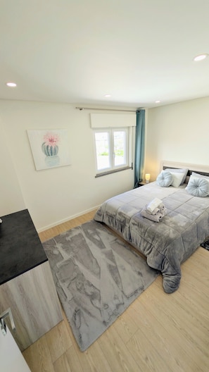 Une chambre à coucher avec un lit, une table de chevet, une fenêtre et un tableau au mur.