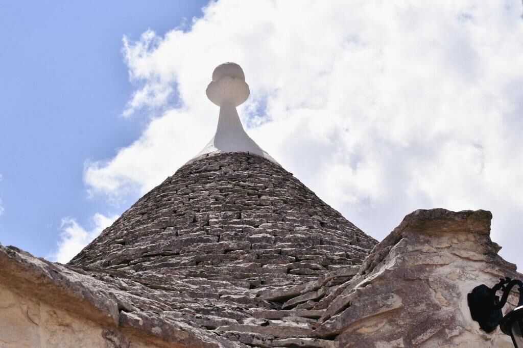 Una estructura piramidal de piedra con un pico, rodeada de muros de piedra.