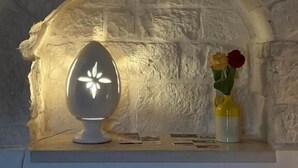 Une cheminée en pierre, agrémentée d’un luminaire moderne et d’un vase rempli de fleurs.