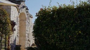 Un bâtiment en pierre, avec un étroit sentier menant à une arche, le tout entouré de verdure et illuminé de guirlandes lumineuses.