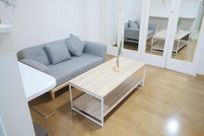 A modern living room with a grey sofa, a wooden coffee table, and a white side table. - 長滞在割引あり★一棟貸切独立和風一戸建★完全非接触★設備・備品完備★Free Wifi (Ikuno Ward, Osaka)