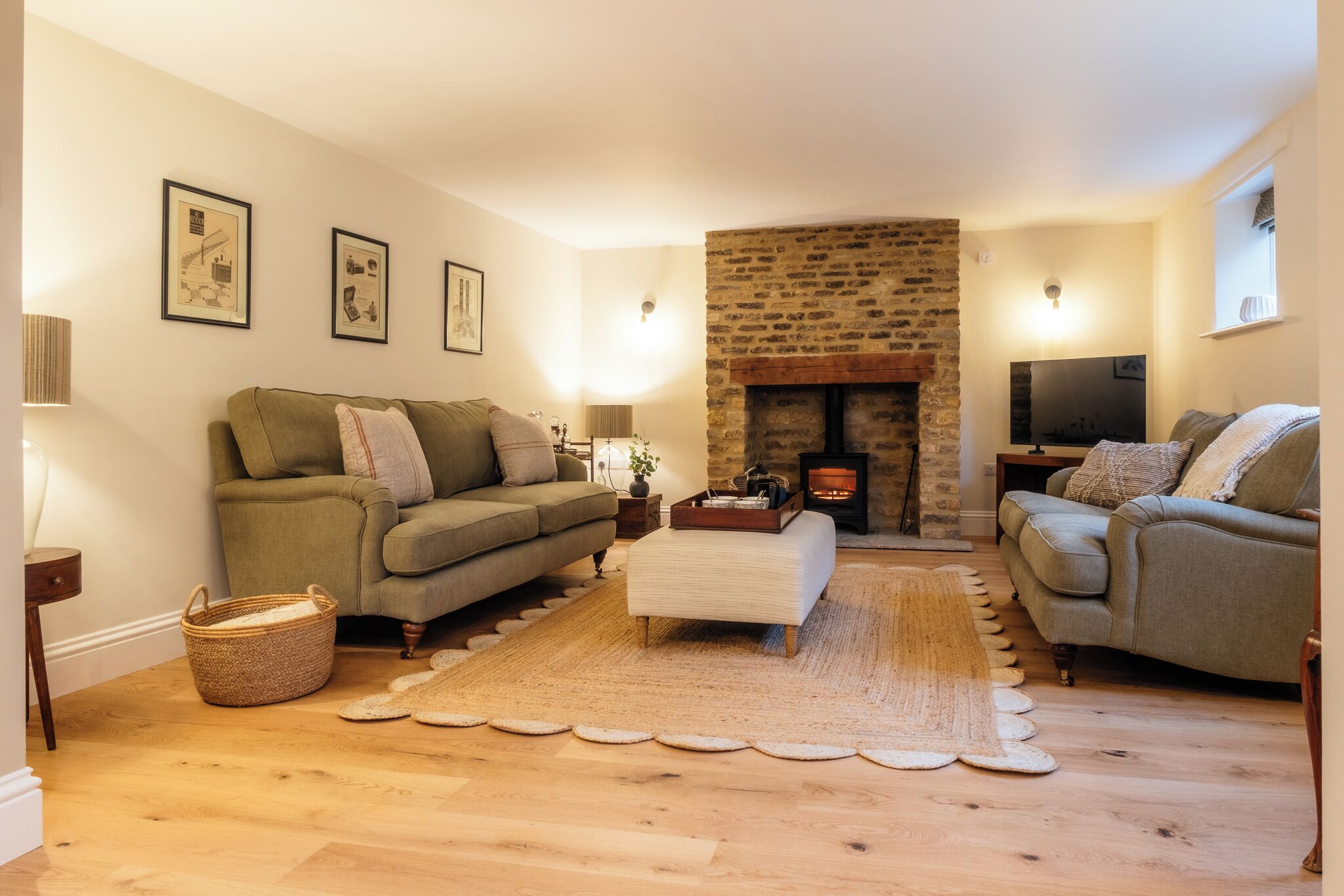 A cozy living room with a fireplace, two sofas, a coffee table, and framed pictures on the wall.