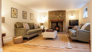 A cozy living room with a fireplace, two sofas, a coffee table, and framed pictures on the wall.