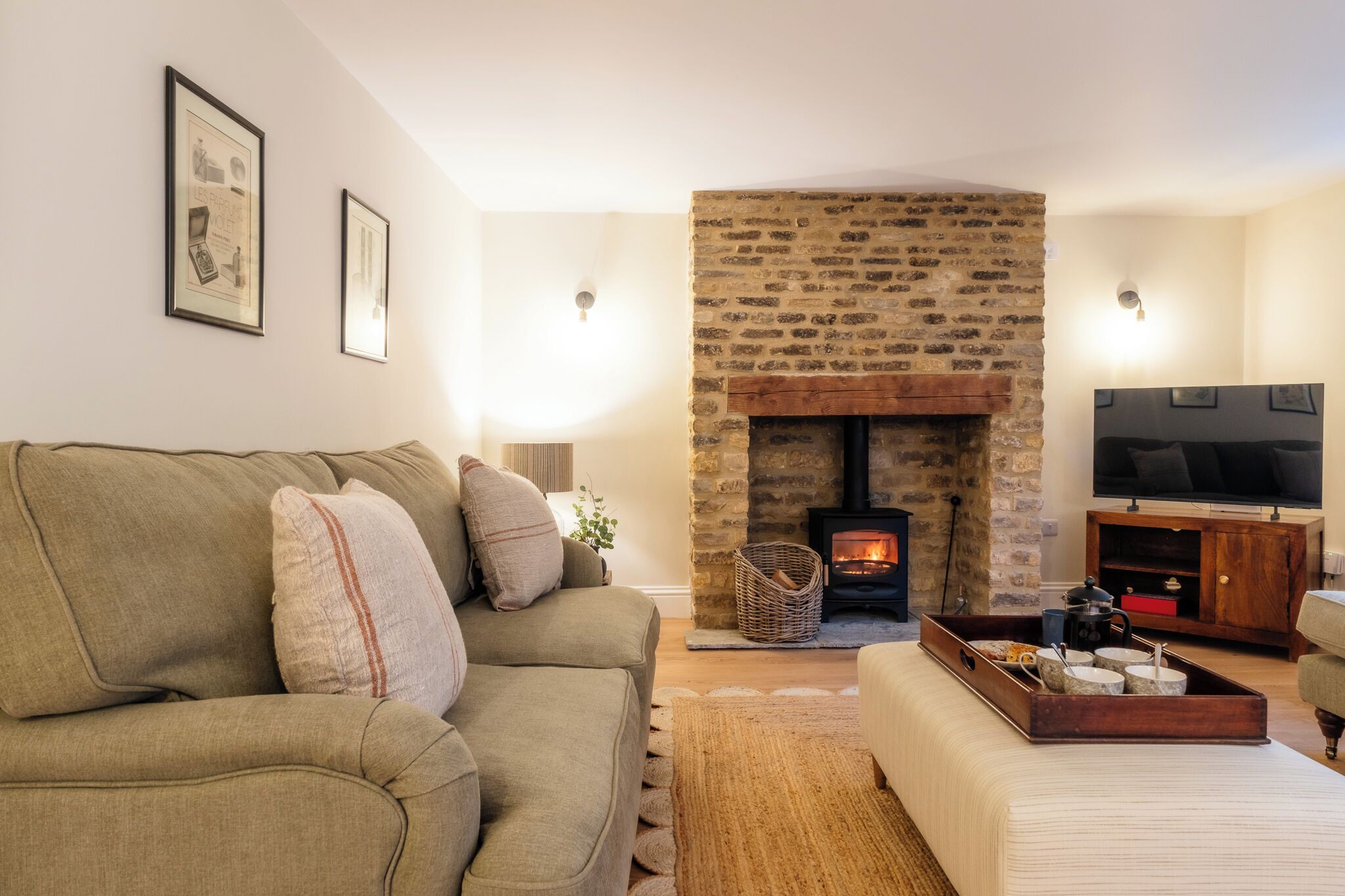 A living room with a stone fireplace, a sofa, a television, and a wooden coffee table.
