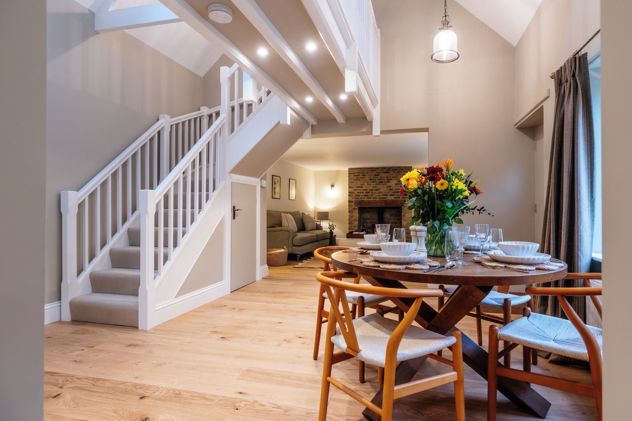 A dining area with a round table, chairs, and a staircase.
