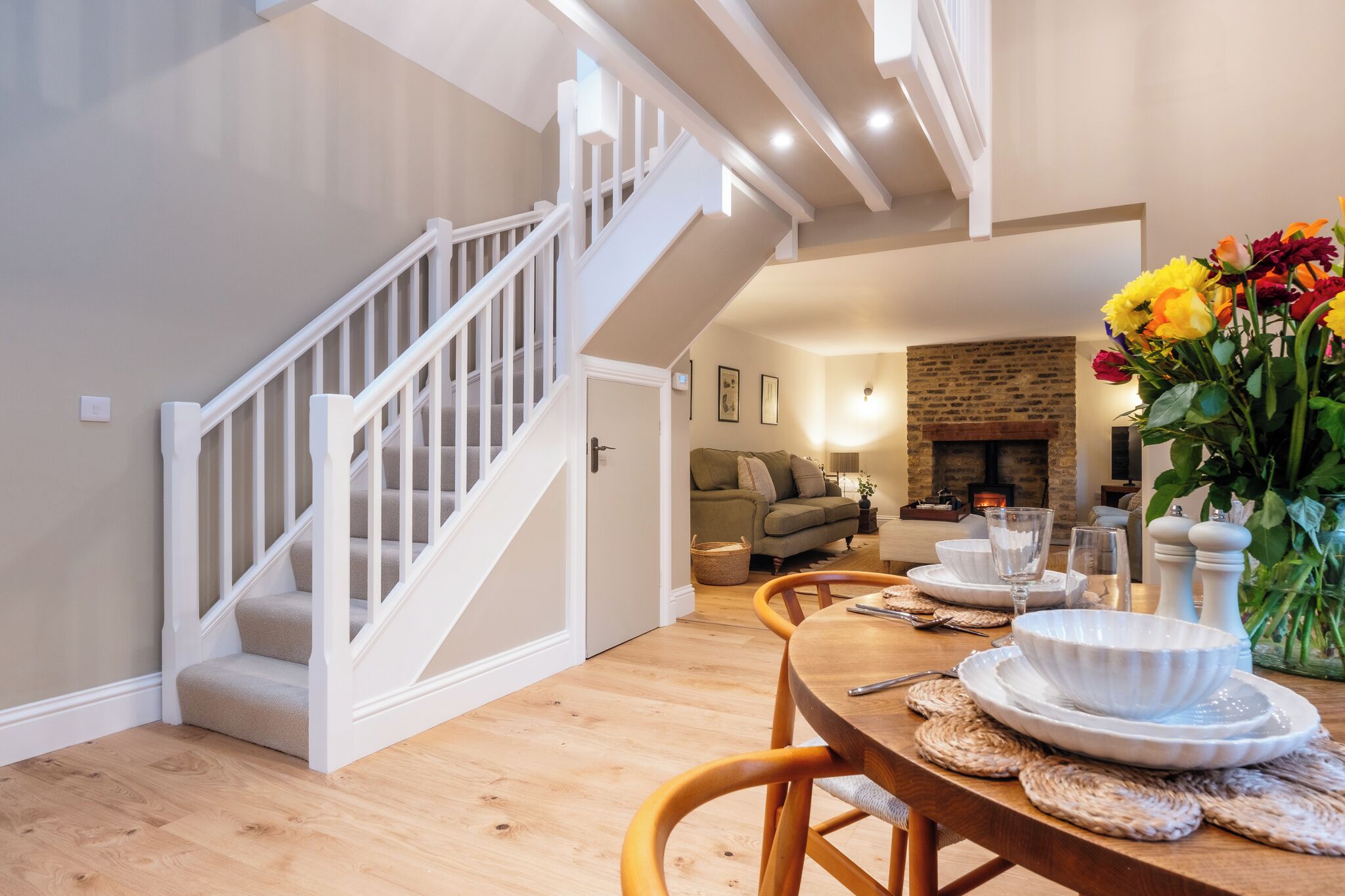 A dining area with a wooden table, chairs, and a staircase.