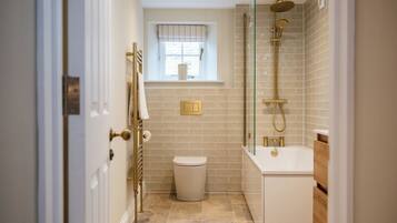 A bathroom with a toilet, a window, a shower, and a bathtub.