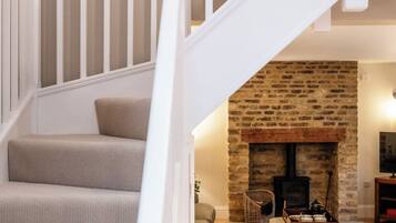 A staircase with white railings leading to a living area with a stone fireplace and a sofa.