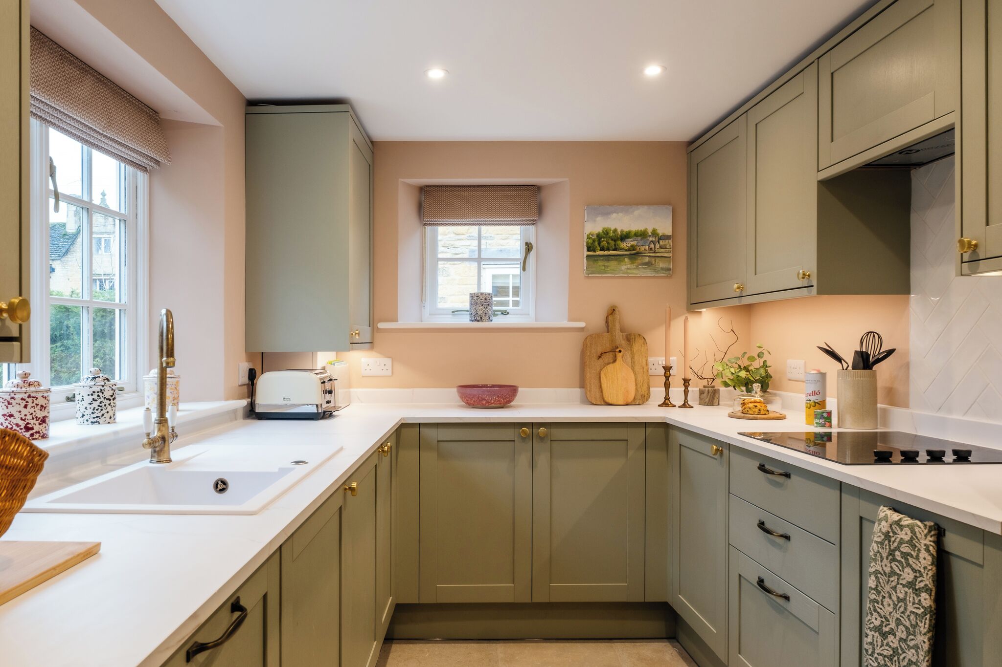 A kitchen with a white countertop, a window with a view, and a painting on the wall.