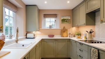 A kitchen with a white countertop, a window with a view, and a painting on the wall.
