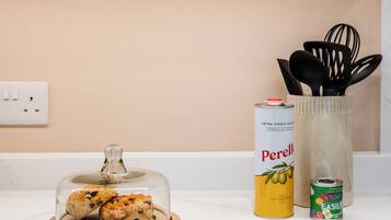 A kitchen counter with a glass dome containing cookies, a can of Perelle, and a can of FASILLO.
