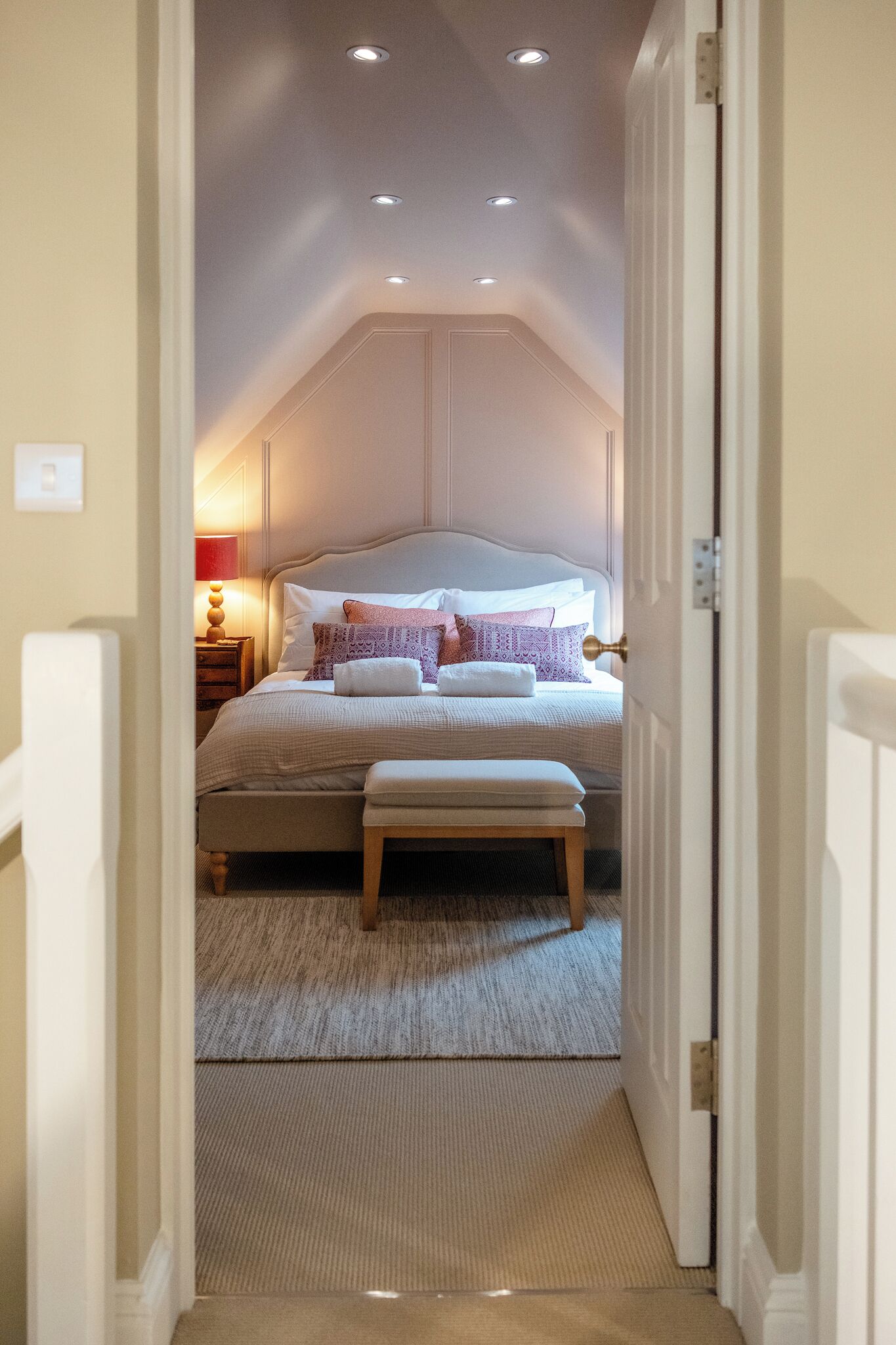 Una camera da letto con un letto, comodino, lampada e pavimento tappezzato.