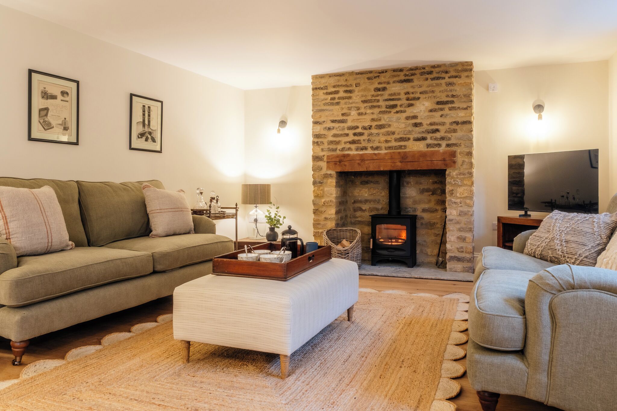 Una sala de estar acogedora con chimenea de piedra, un sofá, una mesa de centro y un televisor.