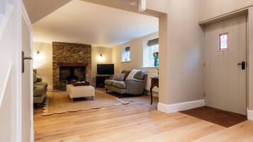 A living room with a fireplace, a sofa, a television, and a wooden floor.