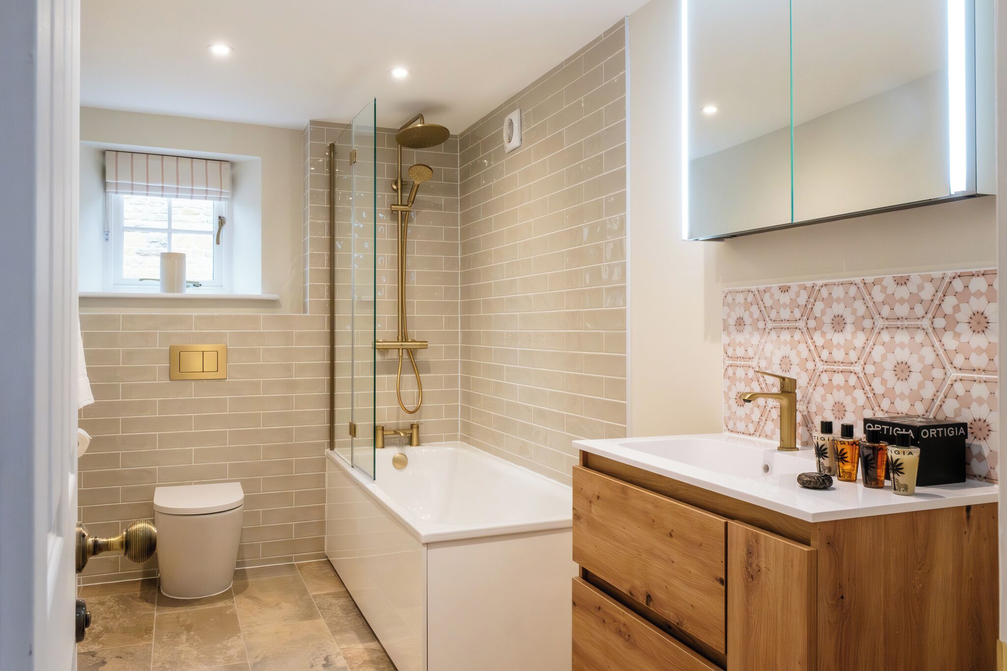 A modern bathroom with a bathtub, toilet, and vanity with toiletries.