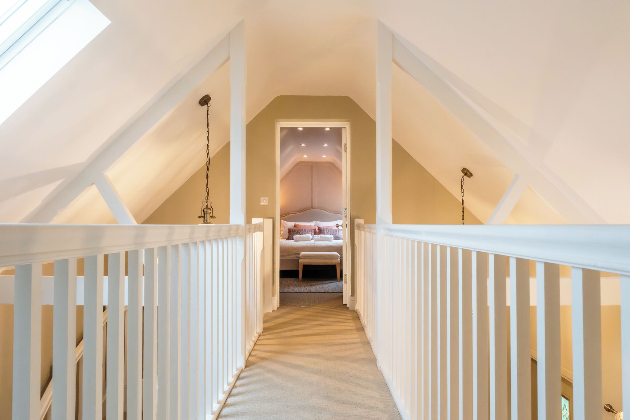 A narrow staircase leading to a bedroom with a bed, a bench, and a door.
