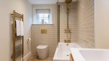 A modern bathroom with a bathtub, toilet, and shower.