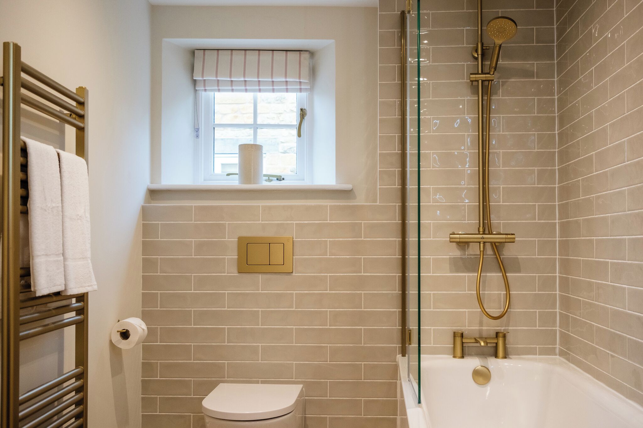 Un baño con bañera, inodoro y una ventana con cortina.