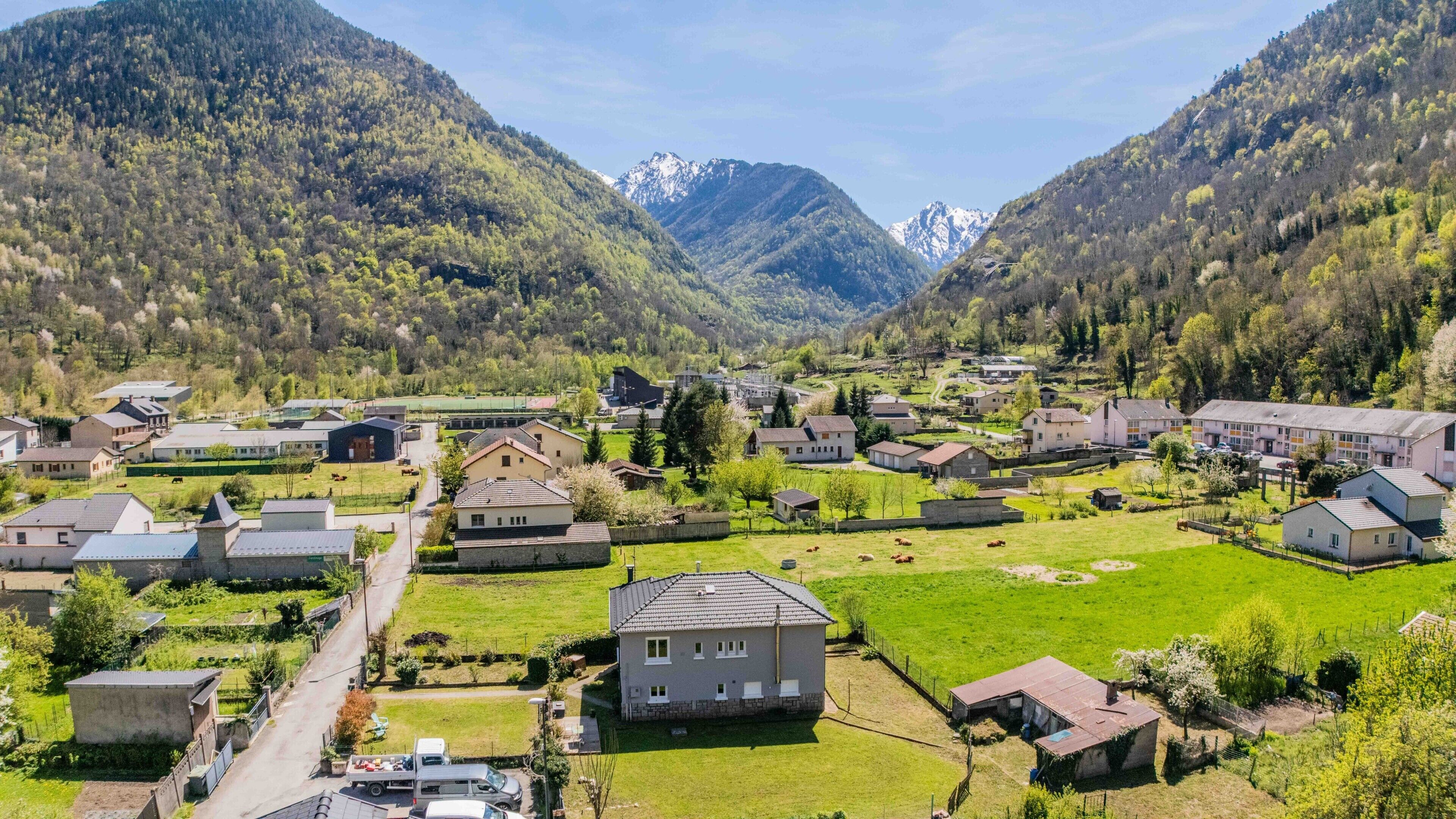 Un pueblo rural con casas, una carretera y montañas al fondo.