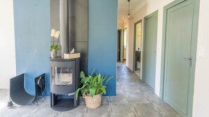 A modern interior with a wood-burning stove, a potted plant, and a hallway leading to a door.