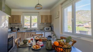 A modern kitchen with wooden cabinets, a dining table set with breakfast, and a view of the outside.