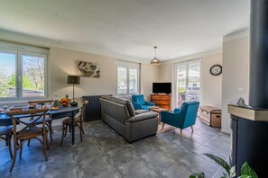 Un salon moderne comprenant un canapé, des fauteuils, une table à manger et un téléviseur.
