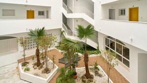 A multi-level atrium with a central garden area, white walls, and balconies. - Beachfront Apartment with Pool, High-Speed Wi-Fi, and Air Conditioning (Almuñécar)