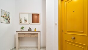 A hallway with a wooden console table, a mirror, and a yellow door. - Beachfront Apartment with Pool, High-Speed Wi-Fi, and Air Conditioning (Almuñécar)