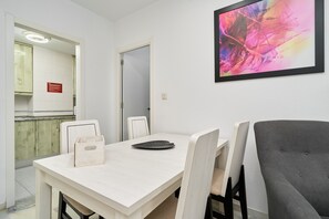 A dining area with a table, chairs, and a framed abstract painting. - Beachfront Apartment with Pool, High-Speed Wi-Fi, and Air Conditioning (Almuñécar)