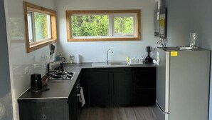 Eine kleine Küche mit Fenster, Spüle, Herd und Kühlschrank.