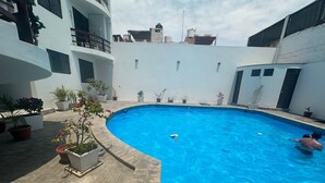 Una piscina a bordo curvo, circondata da piante in vaso e una zona pavimentata.