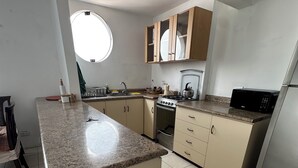 Una cucina con isola centrale, piano cottura, forno a microonde e pensili.