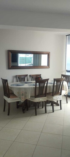 Un coin repas comprenant une table, des chaises et un grand miroir au mur.