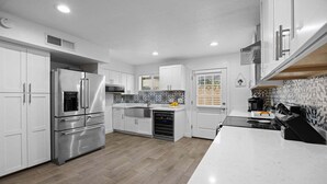 A modern kitchen with stainless steel appliances, white cabinetry, and patterned backsplash. - Eden's Escape Comfort, Style & Prime Phoenix Location (Phoenix)