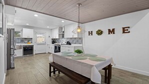A modern kitchen with white cabinets, a dining table with green placemats, and a 'HOME' sign on the wall. - Eden's Escape Comfort, Style & Prime Phoenix Location (Phoenix)