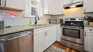 A modern kitchen with white cabinets, stainless steel appliances, and a granite countertop. - NEWLY RENOVATED COZY 2BR 1BA COTTAGE -NEW HOT TUB (Sautee Nacoochee)