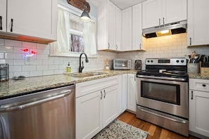 A modern kitchen with white cabinets, stainless steel appliances, and a granite countertop. - NEWLY RENOVATED COZY 2BR 1BA COTTAGE -NEW HOT TUB (Sautee Nacoochee)