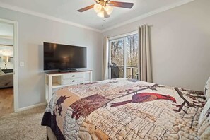 A bedroom with a bed, a TV on a stand, a ceiling fan, and a window with curtains. - NEWLY RENOVATED COZY 2BR 1BA COTTAGE -NEW HOT TUB (Sautee Nacoochee)