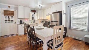 A kitchen with white cabinets, a wooden dining table, and chairs. - NEWLY RENOVATED COZY 2BR 1BA COTTAGE -NEW HOT TUB (Sautee Nacoochee)