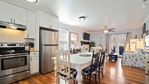 A modern kitchen with white cabinets, stainless steel appliances, a dining area with a white table and black and white checkered chairs, and a ceiling fan. - NEWLY RENOVATED COZY 2BR 1BA COTTAGE -NEW HOT TUB (Sautee Nacoochee)